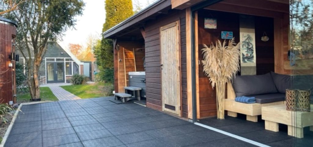 Een bungalow met jacuzzi: de prachtige tuin met links in beeld de sauna, in het midden de jacuzzi en rechts de zithoek!
